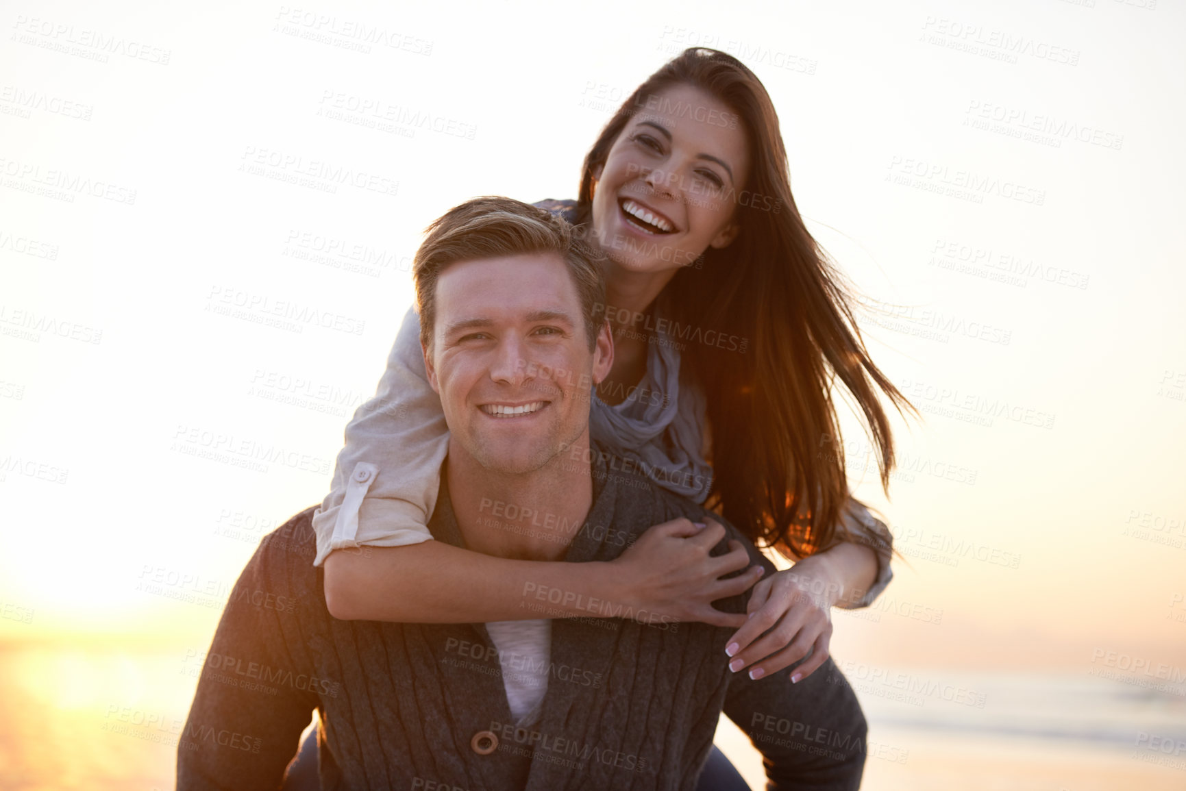 Buy stock photo Portrait, piggy back and couple on beach at sunset for tropical holiday adventure, relax and bonding together. Love, happy man and woman on romantic date with ocean, evening sky and vacation