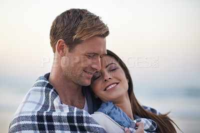 Buy stock photo Couple, hug and happy at beach with blanket for vacation, love and care on date at sunset by ocean. Man, woman and embrace with smile, bonding and happy for memory on holiday by sea in Australia