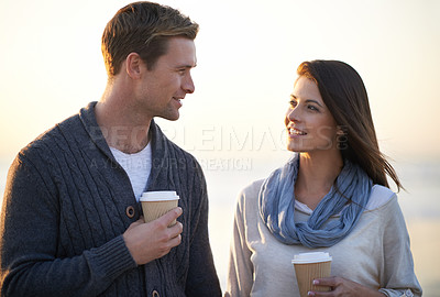 Buy stock photo Couple, coffee and sunset by ocean on vacation, walking and conversation in summer at beach. Man, woman and drink with tea cup with smile, bonding and happy for memory on holiday by sea in Australia