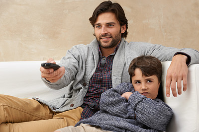 Buy stock photo Shot of father and son sitting on the sofa and surfing through TV channels