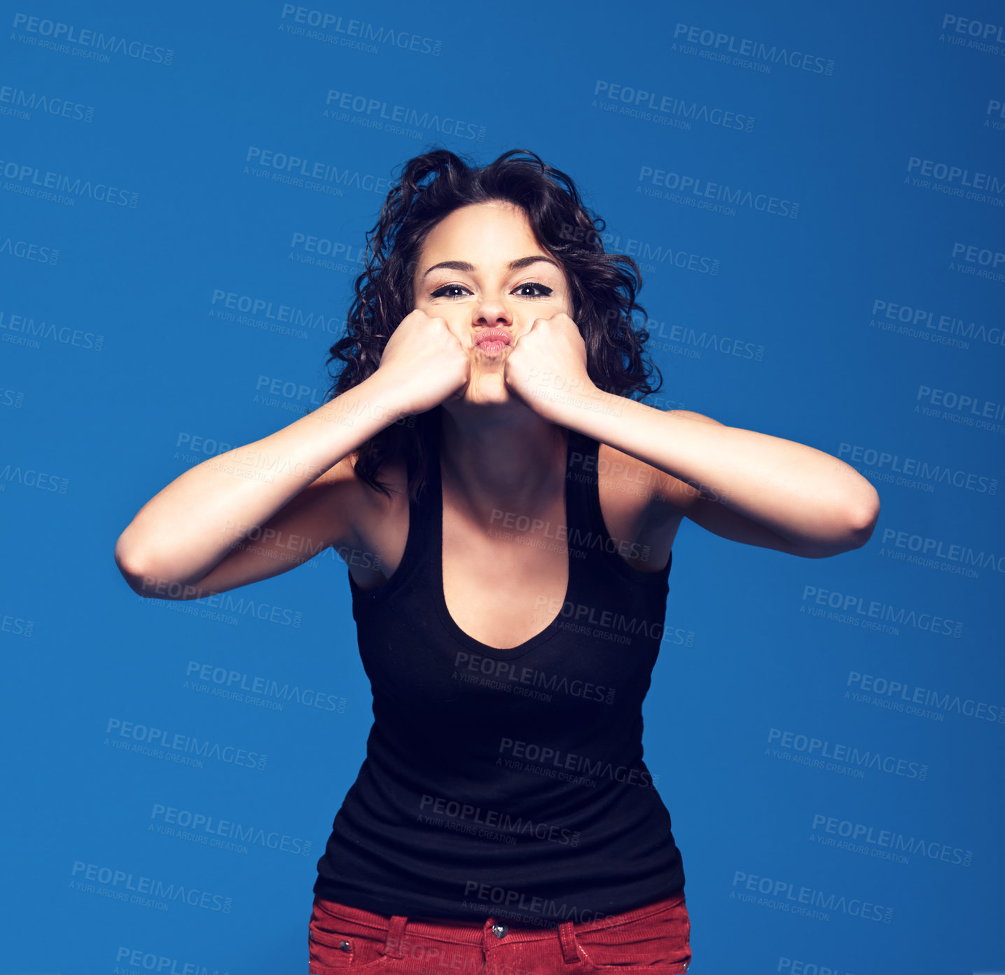 Buy stock photo Studio portrait of a young woman pressing her fists against her face