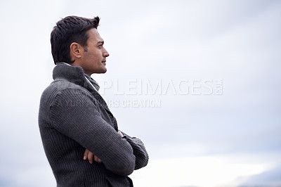 Buy stock photo Shot of a handsome man standing against a cloudy sky