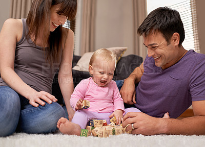 Buy stock photo Shot of a young couple watching their infant daughter play