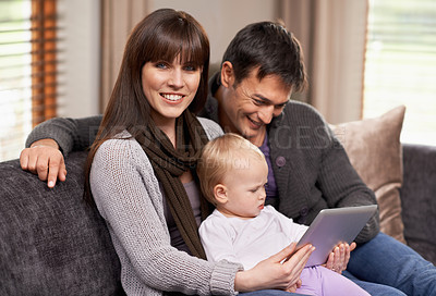 Buy stock photo Digital, tablet or baby with parents on a sofa for cartoon, streaming or videos while bonding at home. Search, learning and family in living room with storytelling app, fantasy or child development