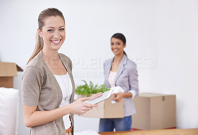 Buy stock photo Two young female colleagues moving into their new office