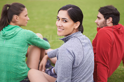 Buy stock photo Portrait of young people in exercise clothing sitting on a grassy sports field