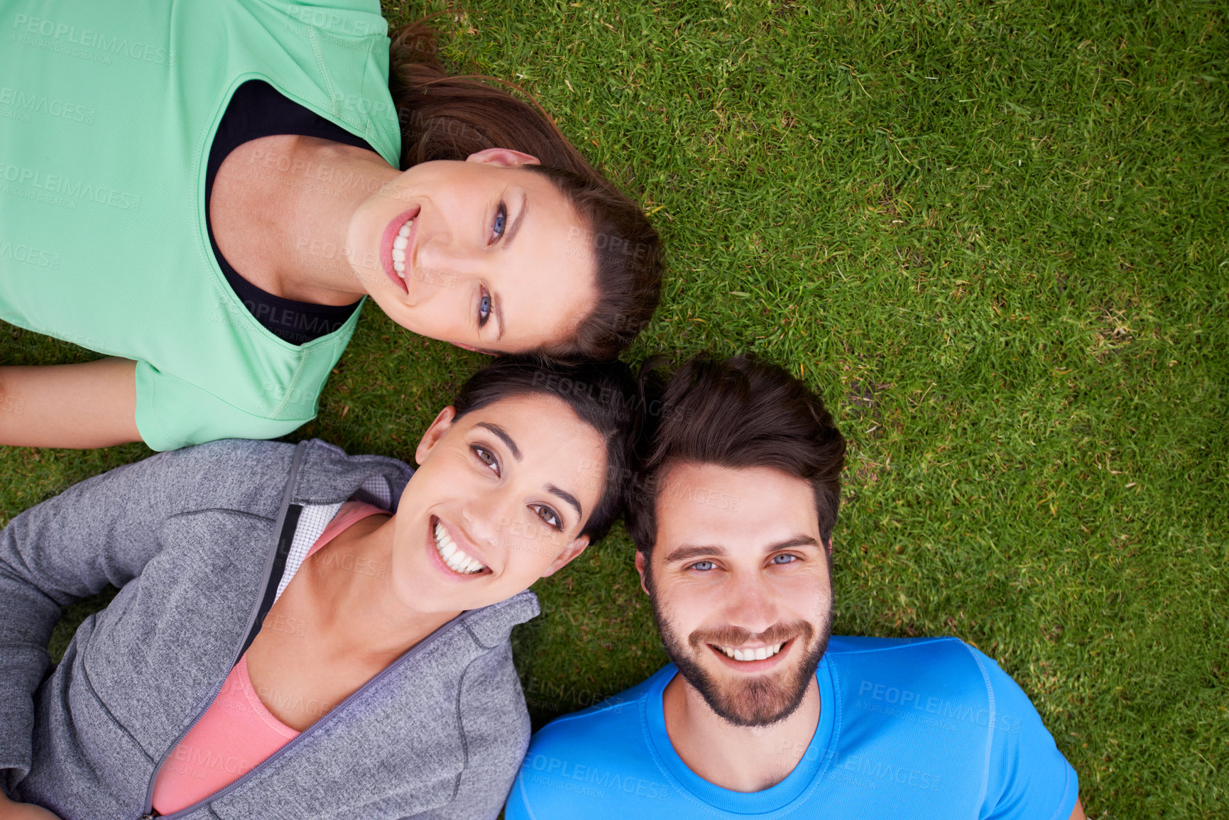 Buy stock photo High angle shot of a three friends lying down on grass