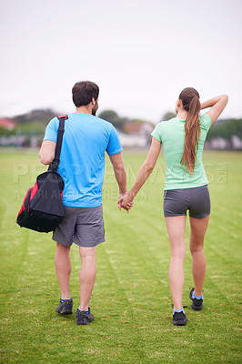Buy stock photo Couple, holding hands and back in park for workout, walking or training for wellness with bag in summer. People, man and woman for support, care or bonding on lawn for exercise for fitness in England