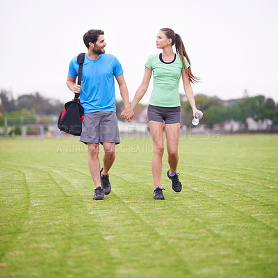 Buy stock photo Couple, holding hands and walk in park for workout, chat and training for wellness with bag in summer. People, man and woman for support, care or bonding on lawn for exercise for fitness in England