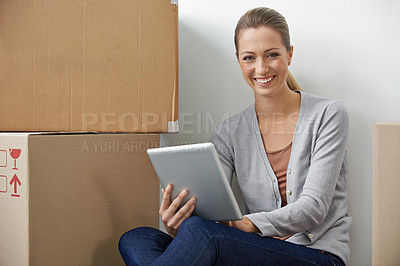 Buy stock photo A young woman working on her digital tablet while sitting next to boxes