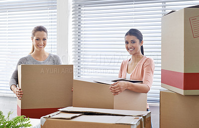 Buy stock photo Shot of two smiling businesswomen moving into a new office