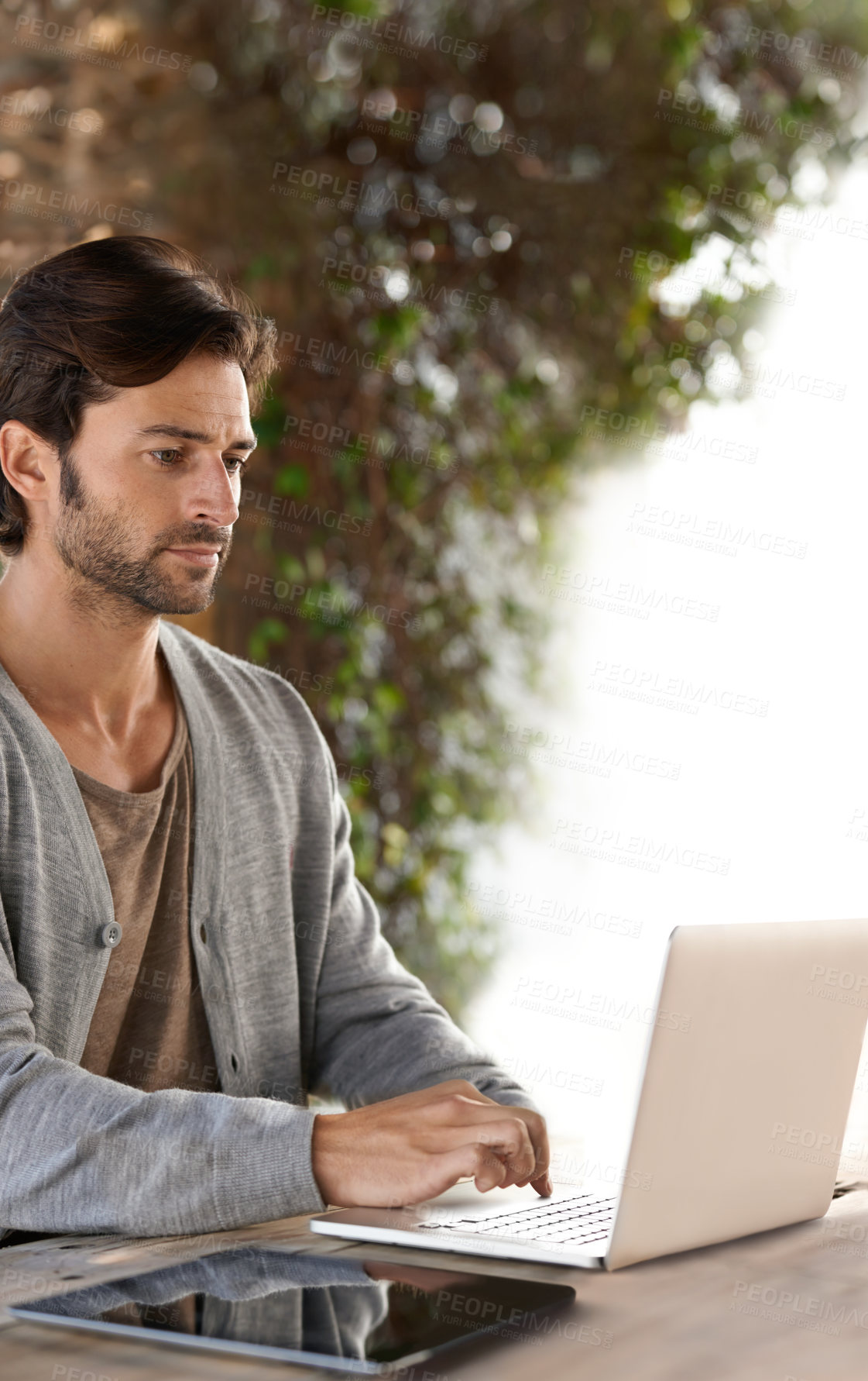Buy stock photo A handsome young man working on his laptop outdoors