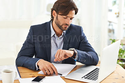 Buy stock photo A handsome businessman checking the time on his watch at his desk