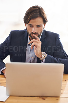 Buy stock photo A handsome businessman sitting at his desk and working on his laptop