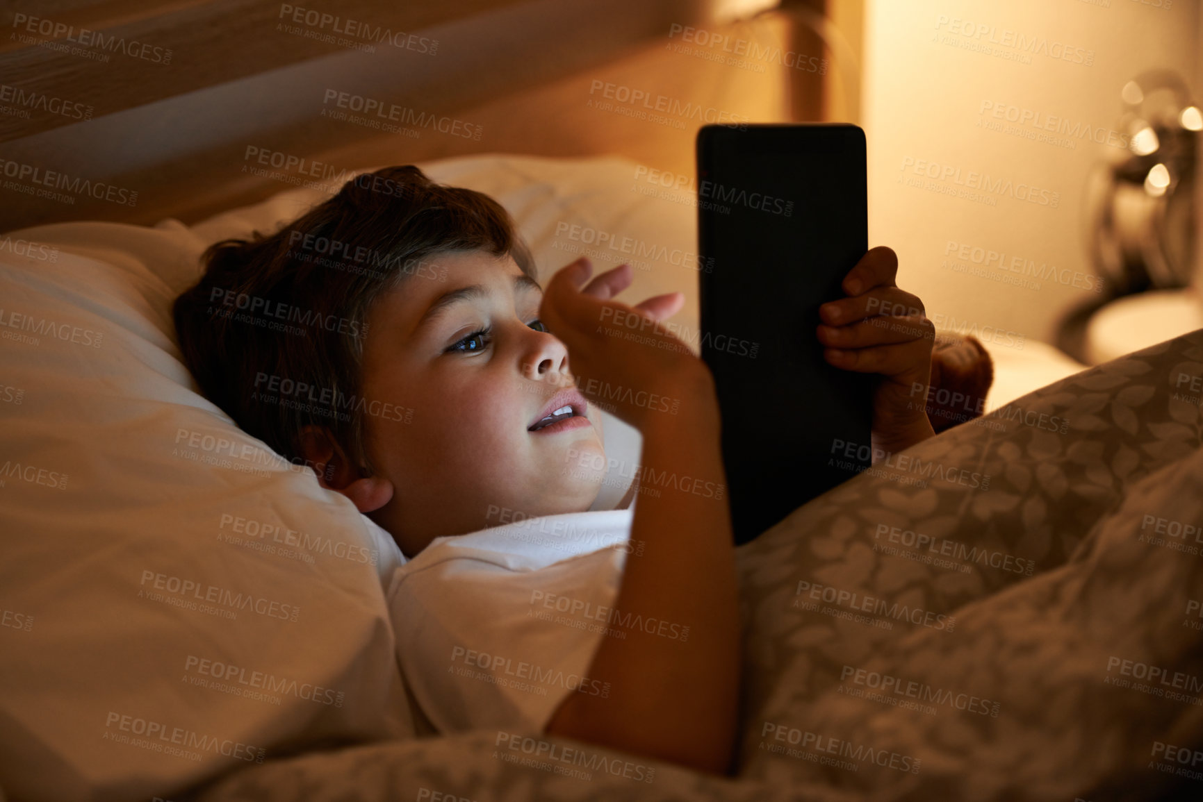 Buy stock photo Boy, tablet and bed with night, digital and technology for social media or learning. Child, bedroom and connectivity for knowledge, youth and elearning or internet surfing at home with touchscreen
