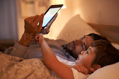 Buy stock photo A father reading a bedtime story to his son from an e-reader