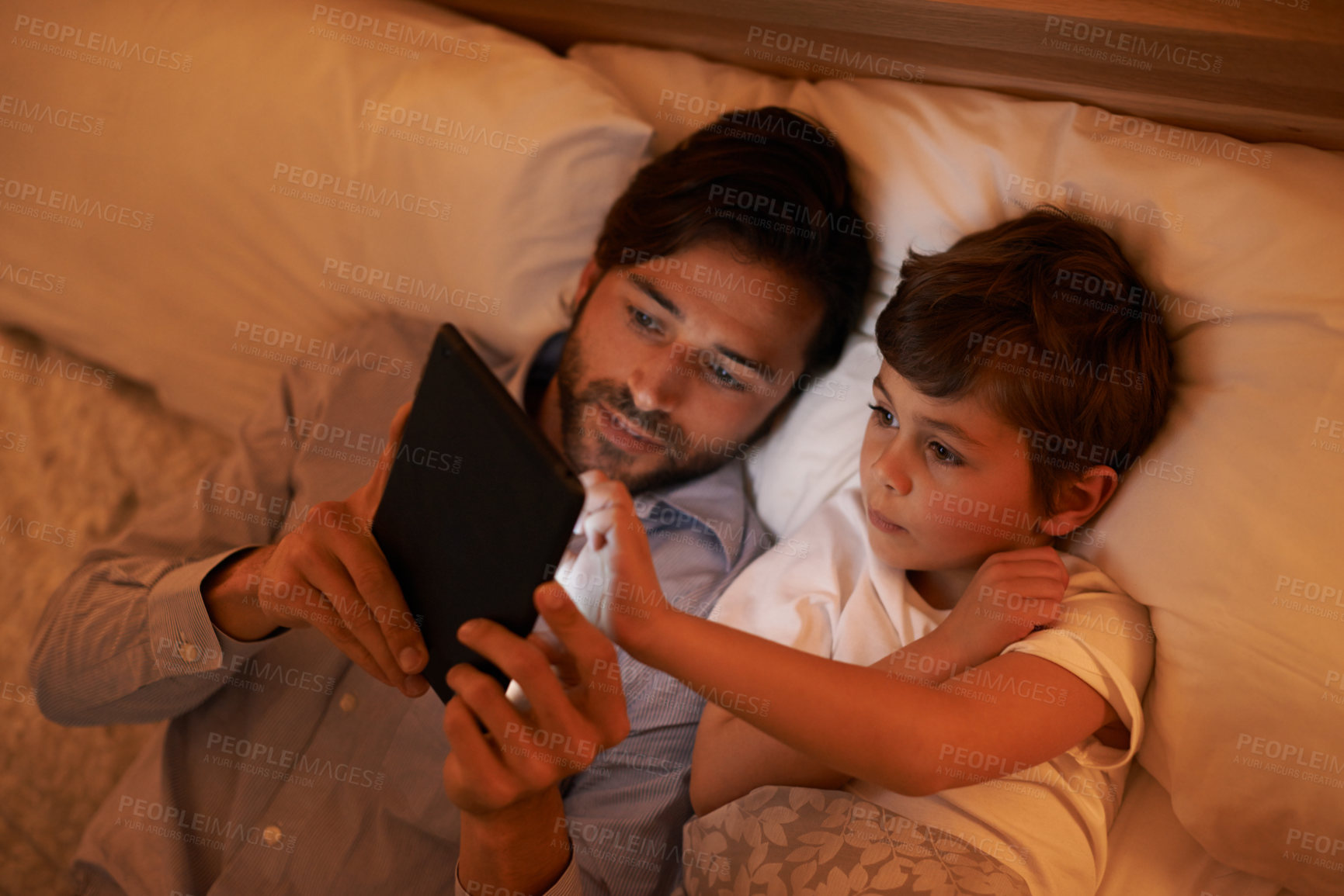 Buy stock photo Bedroom, father and son with tablet, evening and family with ebook and connection with social media. Dad, home and boy with tech or bedtime with lights or bonding together with hobby or storytelling