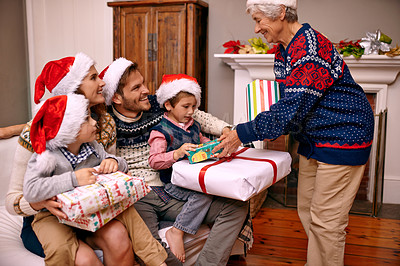 Buy stock photo Christmas, big family and giving gift in living room with smile, gratitude and bonding together in home. Grandmother, parents and children with present, love and festive holiday celebration on sofa.