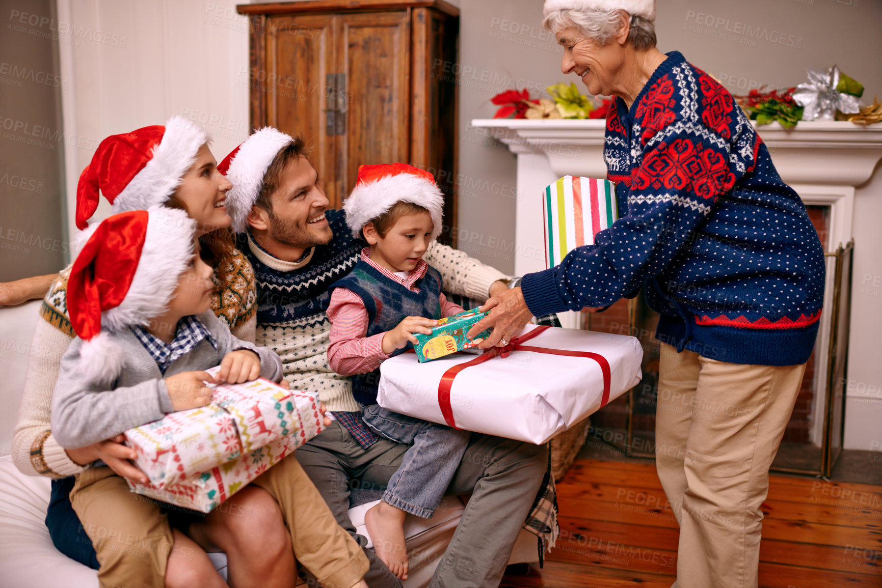Buy stock photo Christmas, big family and giving gift in living room with smile, gratitude and bonding together in home. Grandmother, parents and children with present, love and festive holiday celebration on sofa.