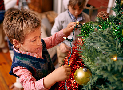 Buy stock photo Little boy, decorating and tree for Christmas with ornaments, lights and celebration for season in season. Child, working and love for festive tradition in family home, kids and enjoying holiday