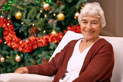 Buy stock photo A happy senior woman sitting on a couch with a Christmas tree behind her