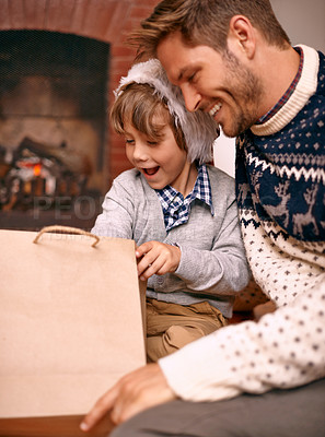 Buy stock photo Father, son and opening gift on Christmas, curiosity and happy for celebrating a festive holiday. Daddy, child and bonding on religious vacation in living room, childhood and tradition of present