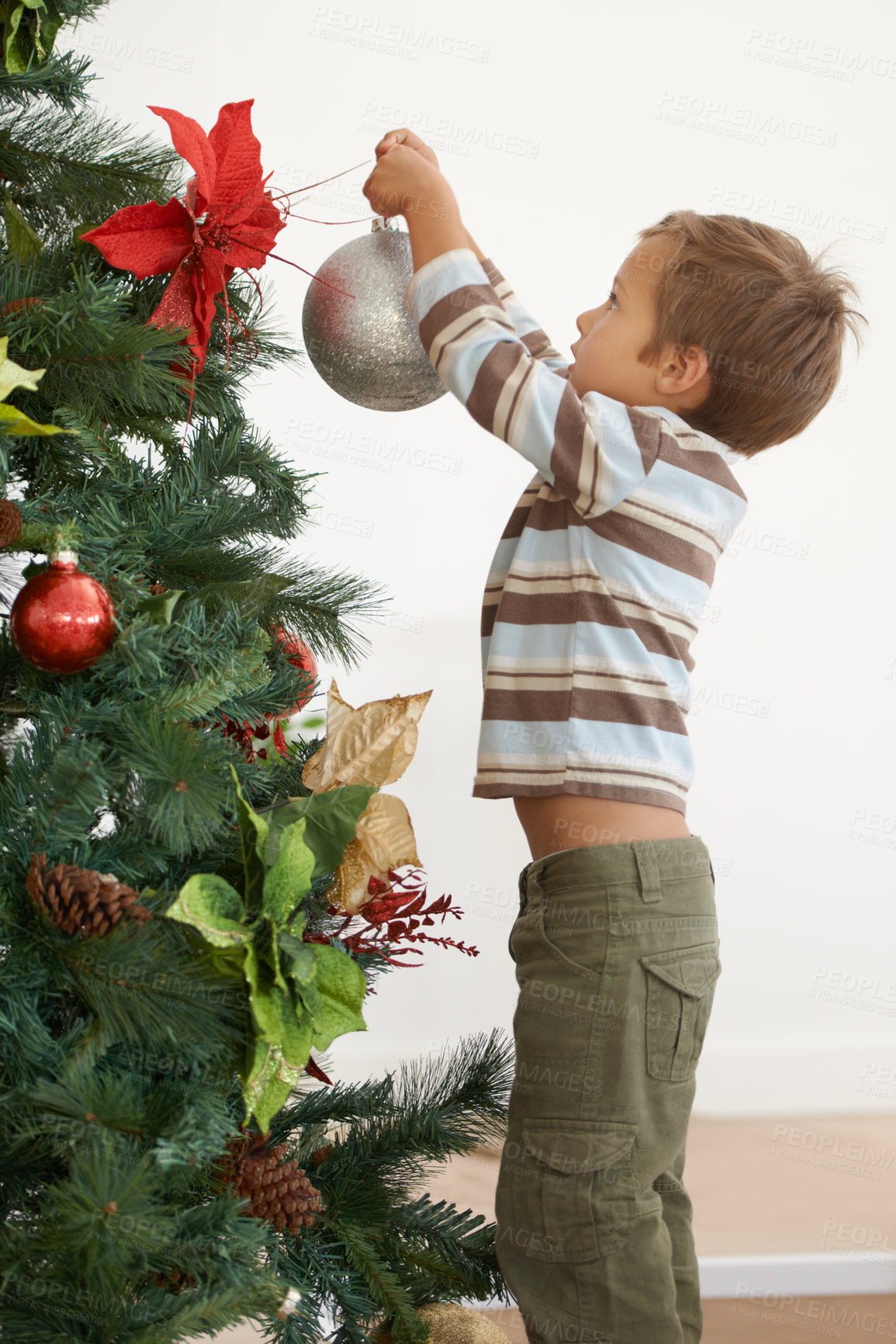 Buy stock photo Shot of a young boy decorating a christmas tree by himself