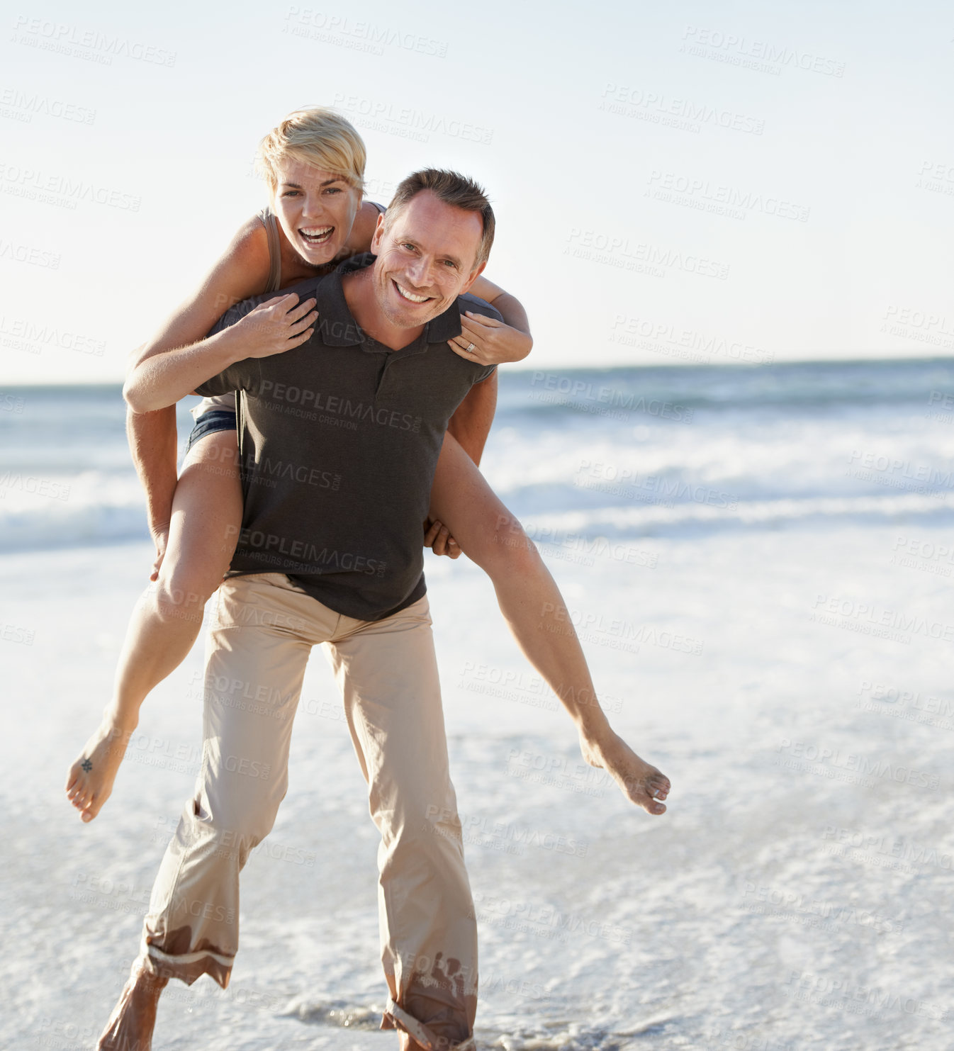 Buy stock photo Couple, portrait and happy on beach with piggyback for bonding, honeymoon date and weekend holiday. Face, man and woman with embrace, smile and love in water by sea for vacation, travel and adventure