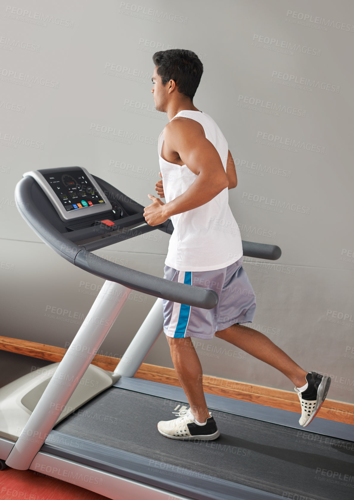 Buy stock photo A young ethnic man running on a treadmill