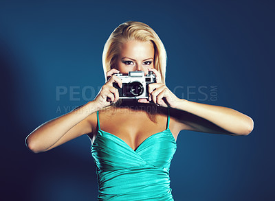 Buy stock photo A pretty young woman holding a camera while isolated on a blue background