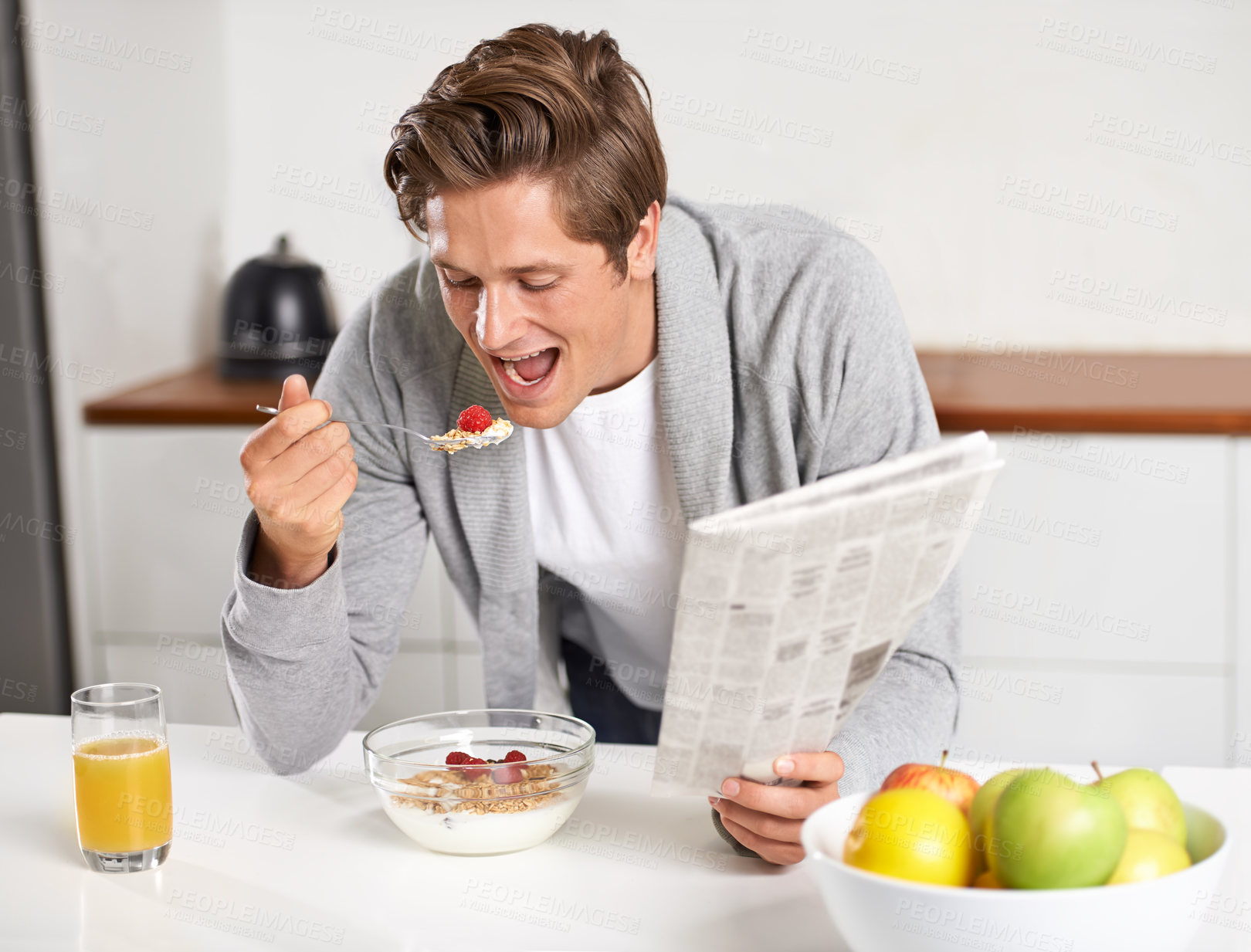 Buy stock photo Cereal, juice and man with newspaper in kitchen for information at modern apartment. Nutrition, breakfast and young male person drinking healthy beverage and reading journalism article at home.