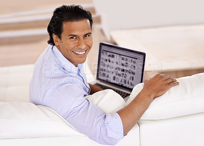 Buy stock photo A handsome young man using his laptop at home