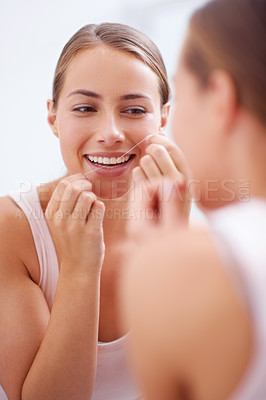 Buy stock photo A young woman flossing her teeth