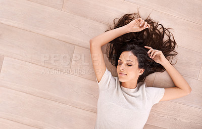 Buy stock photo Studio shot of a beautiful young woman lying on a wooden floor with her arm above her head