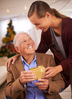 Buy stock photo An attractive young woman giving her father a gift on Christmas