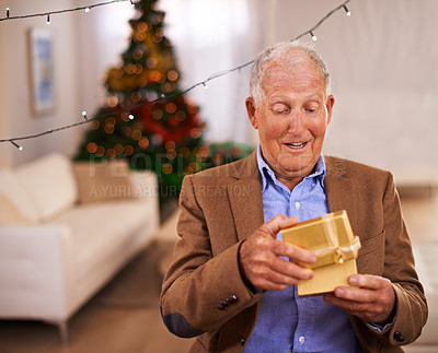 Buy stock photo Christmas, surprise and old man with gift, home and excited with happiness and cheerful in a living room. Pensioner, apartment and elderly guy with present and party with box and retirement with wow
