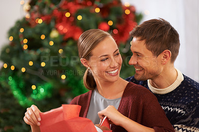 Buy stock photo Love, Christmas gift and couple in living room at home for festive celebration together. Smile, happy and young man and woman with holiday present box for xmas event or party at modern house.