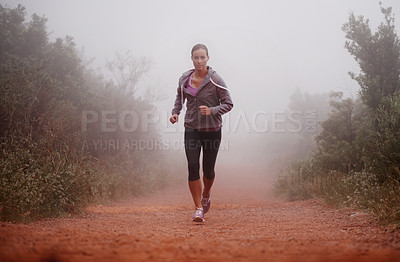 Buy stock photo Shot of a woman running on a trail on a misty morning