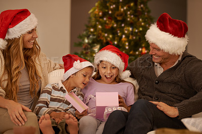 Buy stock photo Parents, girl and children on sofa with Christmas present, surprise and happy with bonding on festive holiday. Mother, father and kids with box, gift and wow for celebration with santa hat on couch