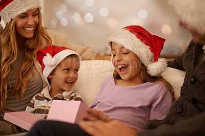 Buy stock photo Christmas, parents and children with gift box on sofa with excited, happy celebration and surprise together. Holiday, festive and mom, dad and kids on couch for present giving, xmas and love in home.