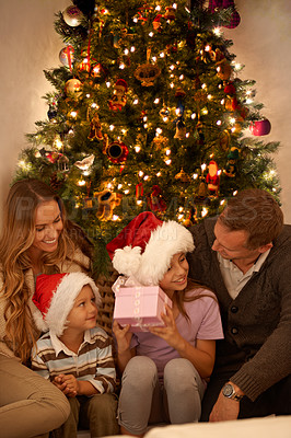 Buy stock photo Christmas, tree and family with gift box, celebration together or lights for happy surprise at night. Father, mother and children smile in living room for present giving, festive xmas or love in home