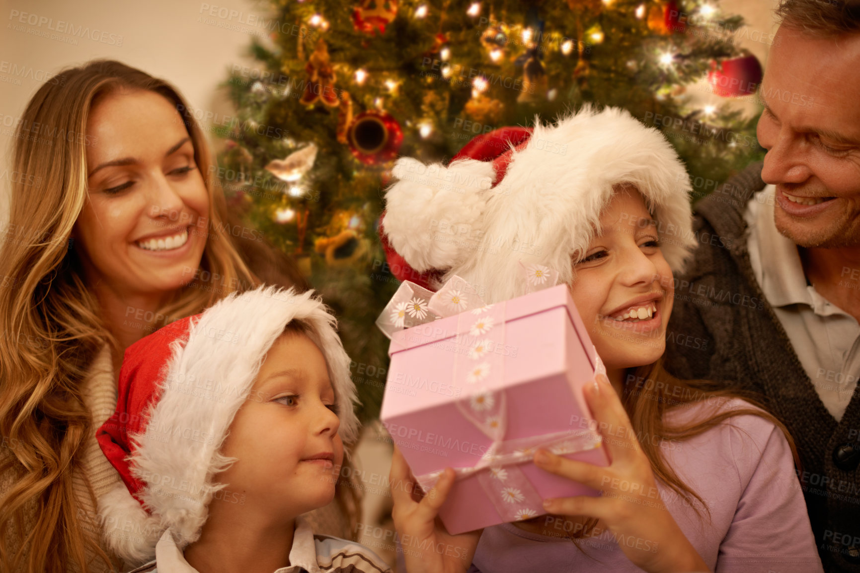 Buy stock photo Christmas, parents and children with gift box at tree for excited, happy celebration and surprise together. Holiday, festive and mom, dad and kids on couch for present giving, xmas and love in home.