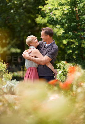 Buy stock photo Happy, hug and couple in a park with love, trust and support, solidarity and security while bonding in nature. Commitment, care and people embrace on a field of flowers for spring romance or date