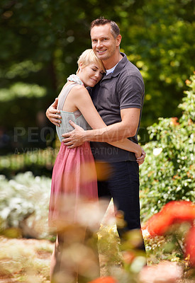 Buy stock photo Hug, happy and couple in a park with love, trust and support, solidarity and security while bonding in nature. Commitment, care and people embrace on a field of flowers for spring romance or date