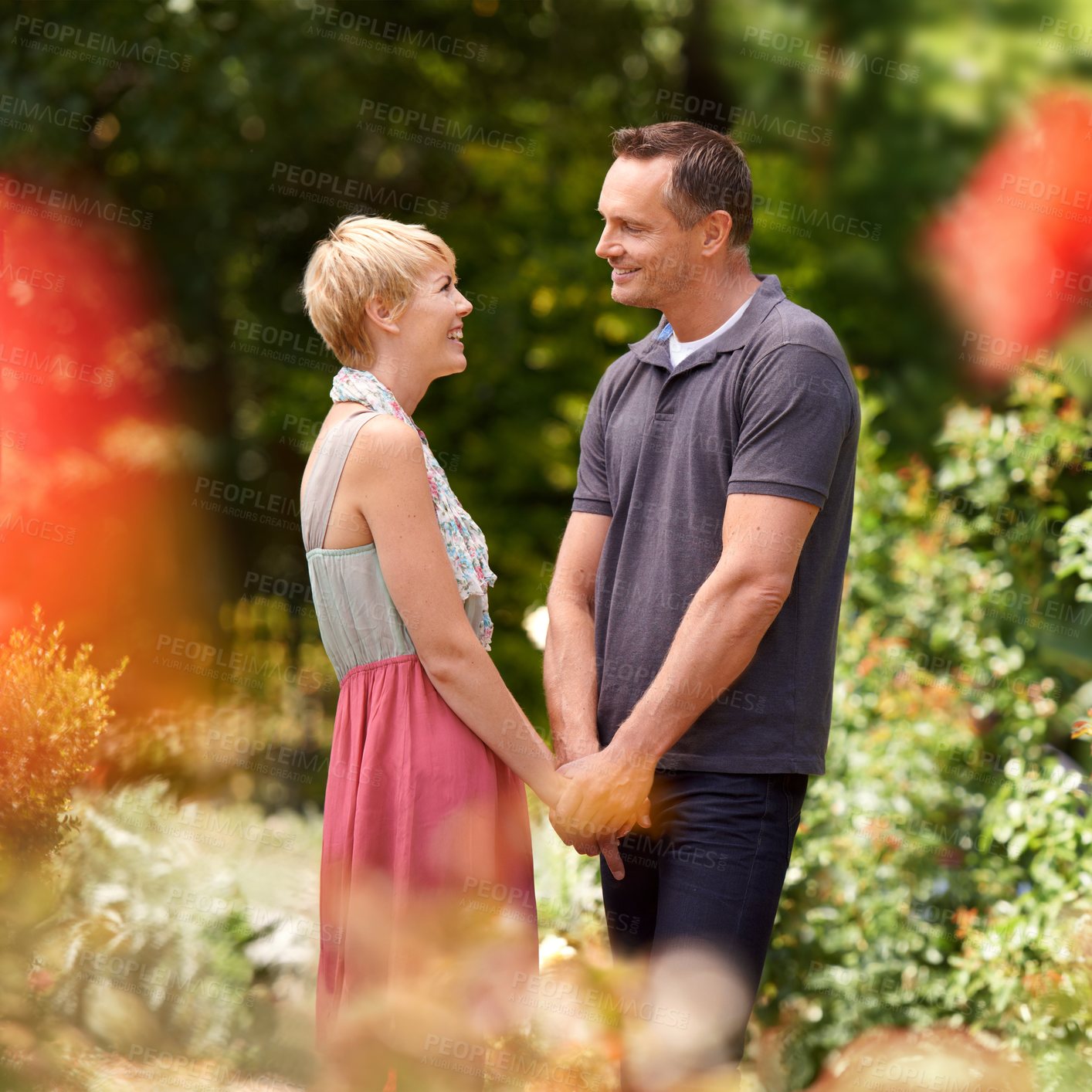 Buy stock photo Happy, holding hands and couple in a park with love, trust and support, solidarity and security while bonding in nature. Commitment, care and people on a field of flowers for spring romance or date