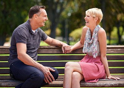 Buy stock photo Love, laughing and happy couple on a park bench with funny conversation, gossip or bonding outdoors together. Trust, communication or people sharing comic, chat or speaking on travel, trip or holiday