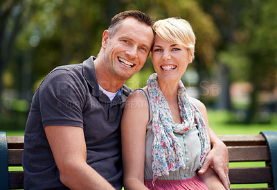 Buy stock photo Shot of a mature couple enjoying a romantic moment on a park bench
