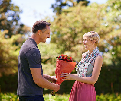 Buy stock photo Smile, couple and present of flowers in nature outdoor, bonding and date on valentines day. Bouquet, man and woman with gift for love, care and romantic connection of people laughing at park together