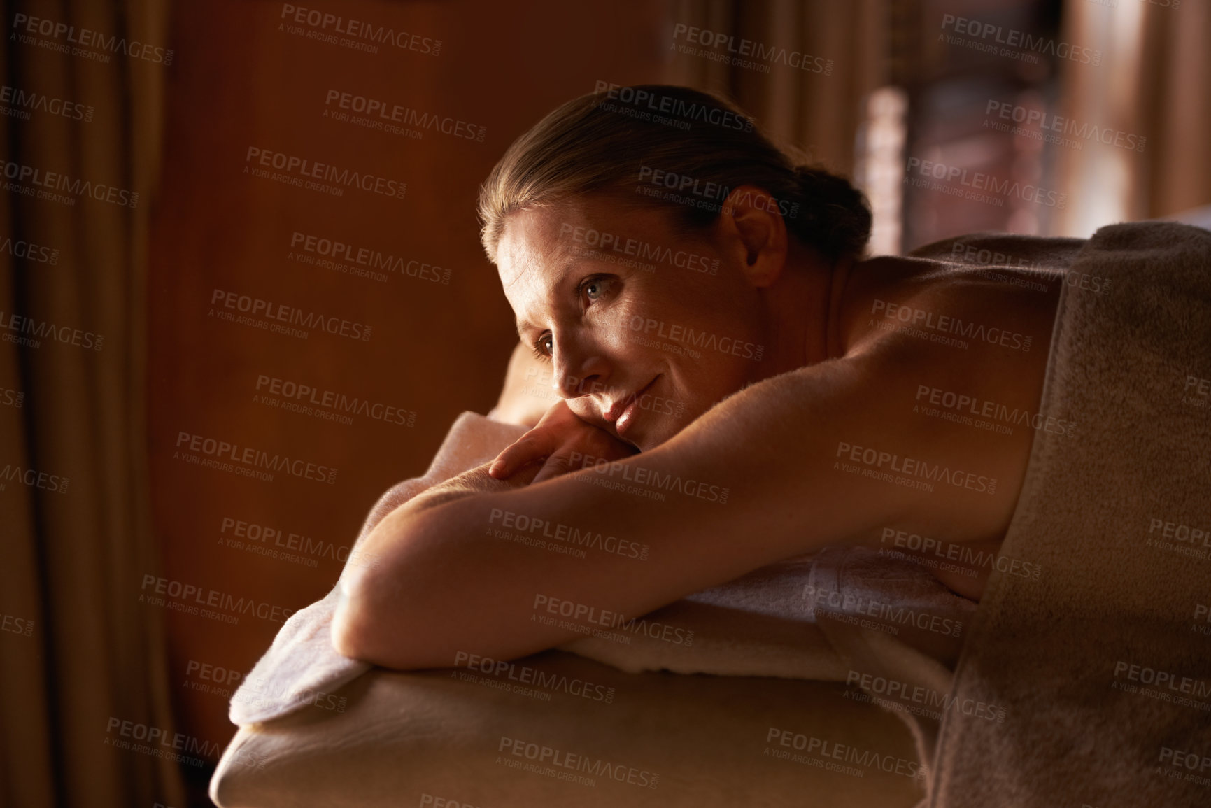 Buy stock photo Woman, happy and lying for wellness, spa and tranquil getaway at luxury retreat in Amsterdam. Smile, calm and mature female person contemplating on massage table for peaceful, treatment and self care