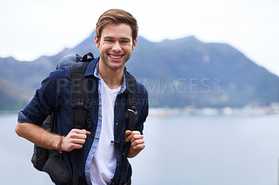 Buy stock photo Portrait of a handsome young man standing with a backpack in the outdoors